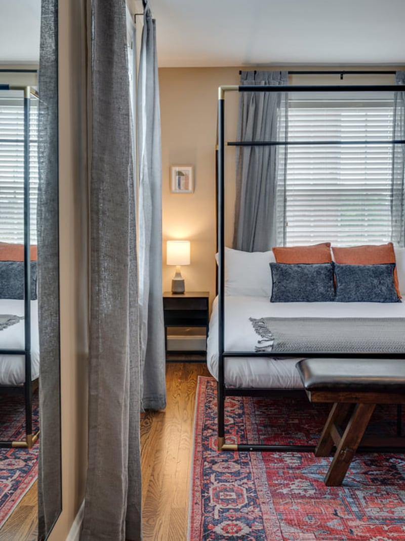 Bedroom with two beds separated by gray curtain divider, patterned rug, and windows with gray curtains
