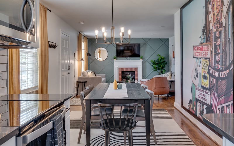 Open-plan kitchen and living room with dining table, fireplace, and vintage music poster on teal accent wall
