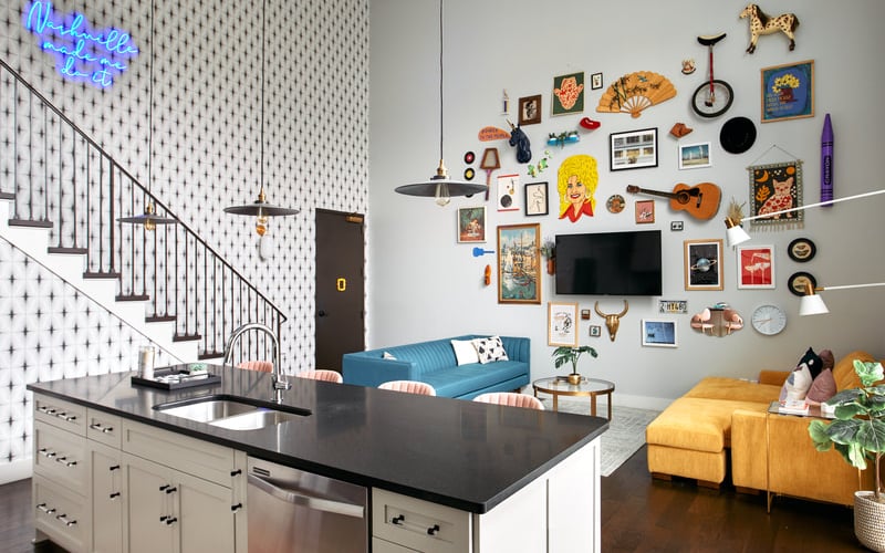 Open-plan living space with kitchen island, blue sofa, and gallery wall of eclectic artwork and vintage decor