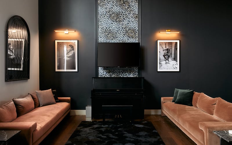 Modern living room with two terracotta sofas facing a black fireplace with TV, dark walls, arched mirror, and framed artwork